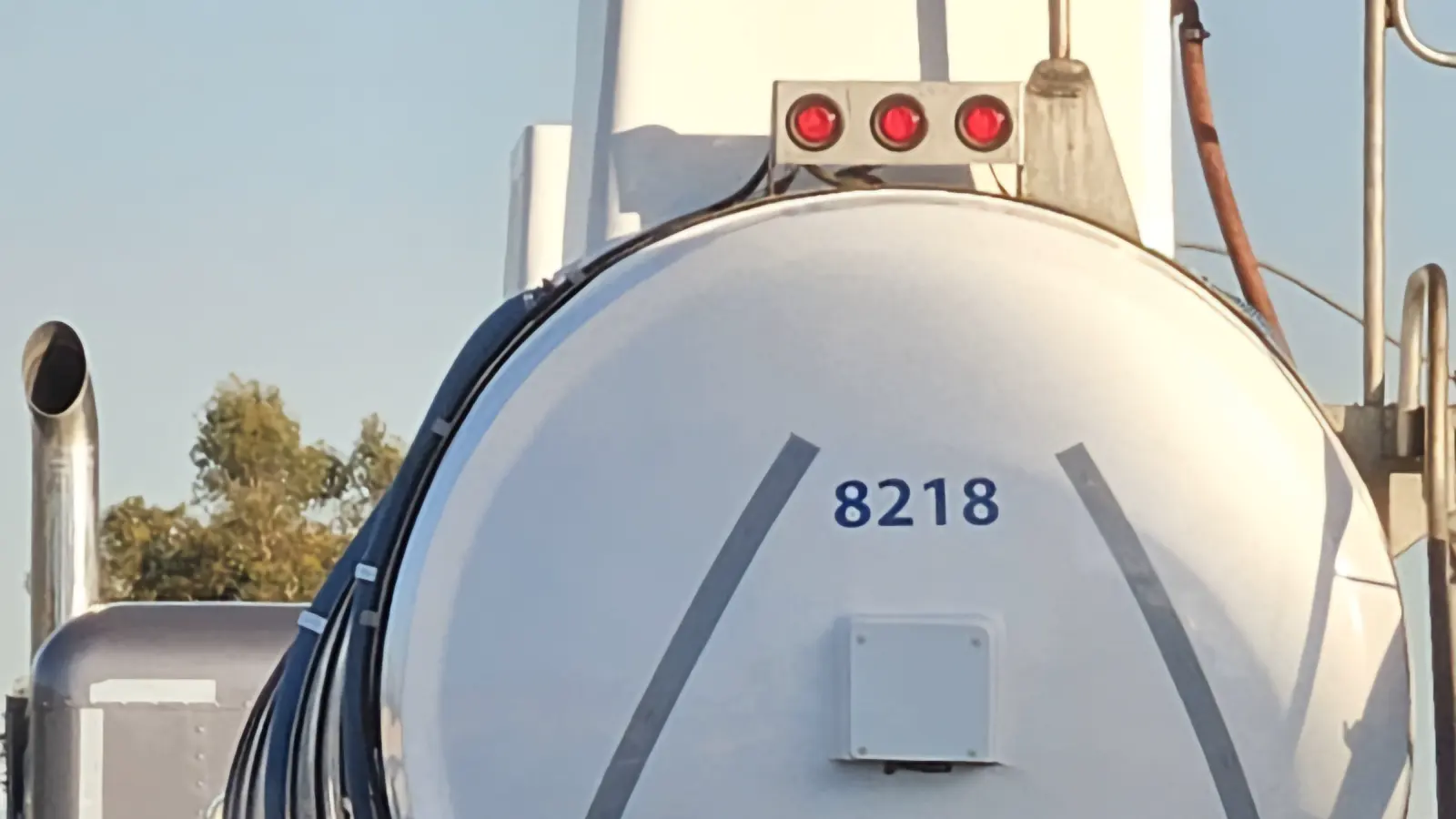 The rear of a white tank trailer, with marker lights above the tank.